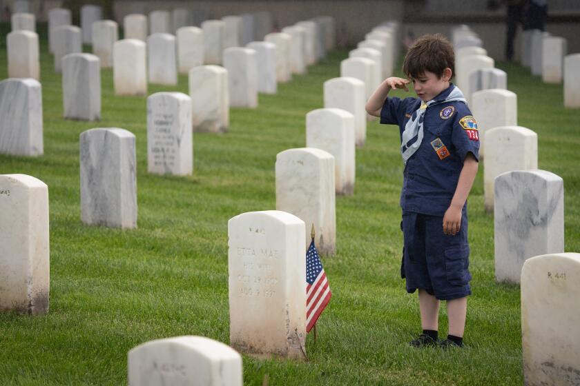 SAN DIEGO, CA - MAY 25: Cub Scout Charley Blake with Pack 734 in Carmel Valley salutes at a grave, after placing a flag in front of it at Fort Rosecrans National Cemetery. He was one of the scouts and their family members who placed flags on more than 89,000 graves at the cemetery Saturday May 25, 2024 in commemoration of Memorial Day, which is Monday May 27. (Howard Lipin / For The San Diego Union-Tribune)