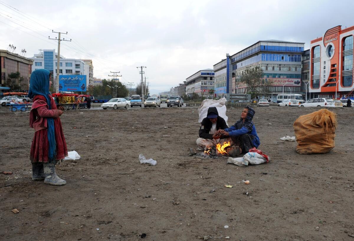 Afghan child laborers sit around a fire on a roadside in Kabul.