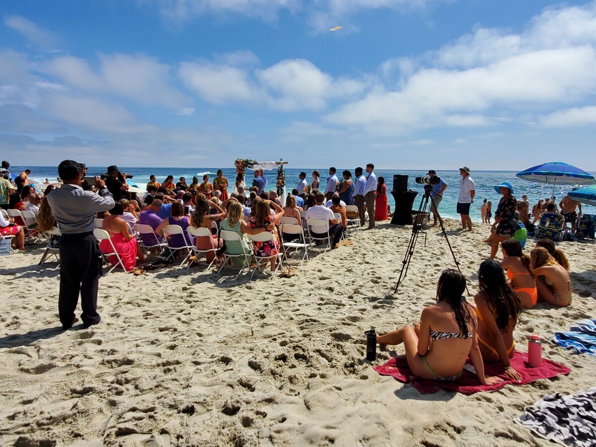 A wedding takes place at Windansea Beach on July 10, with several beach-goers nearby.