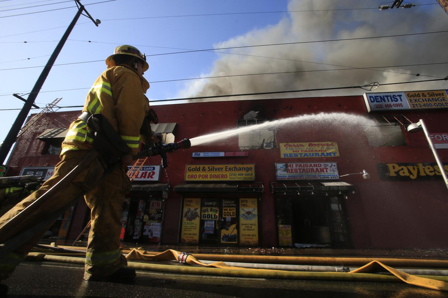 A Los Angeles city firefighter lays a stream of water on a burning two-story commercial building on Santa Monica Boulevard in Hollywood.