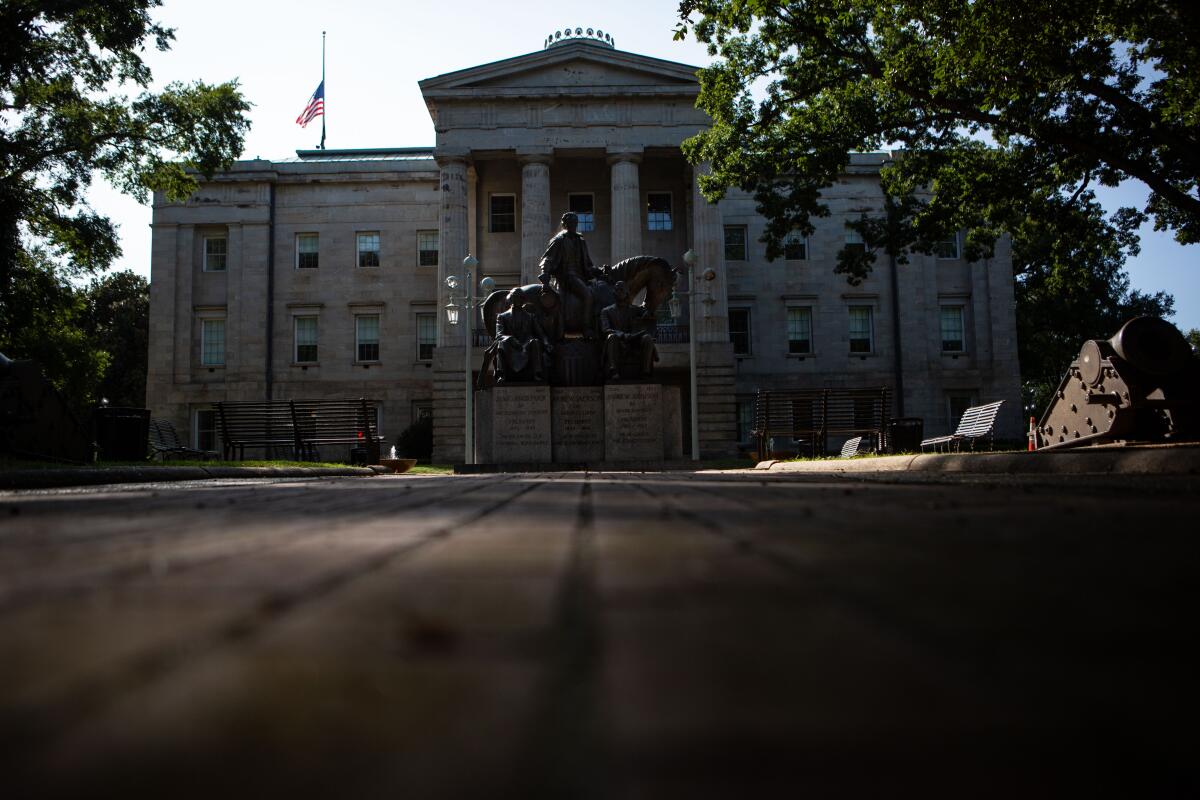 An exterior view of the North Carolina Capitol with a statue of a man on a horse.