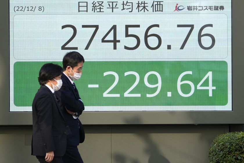 People walk past an electronic stock board showing Japan's Nikkei 225 index at a securities firm Thursday, Dec. 8, 2022, in Tokyo. Shares are mostly lower in Asia after Wall Street sagged under weakness in tech stocks. (AP Photo/Shuji Kajiyama)