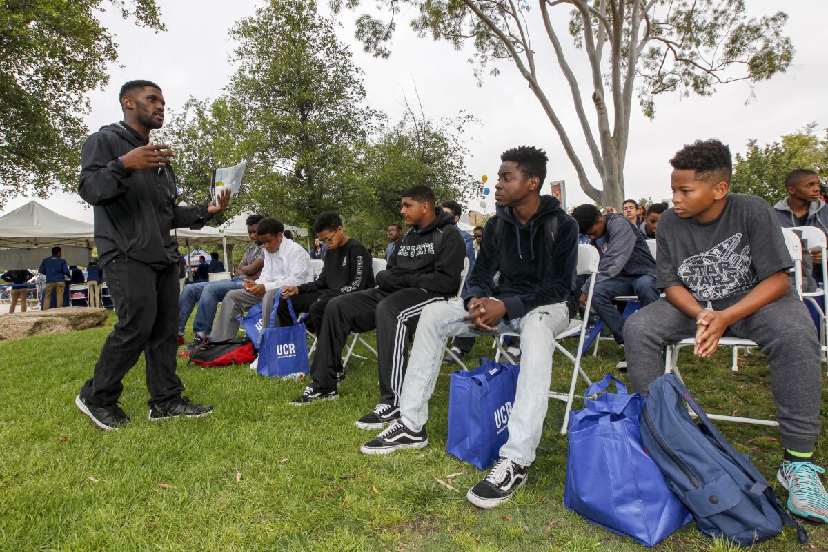 Admissions counselor De'Von Walker, left, speaks to young students visiting UC Riverside through the Council of African American Parents program on Highlander Day. (Irfan Khan / Los Angeles Times)