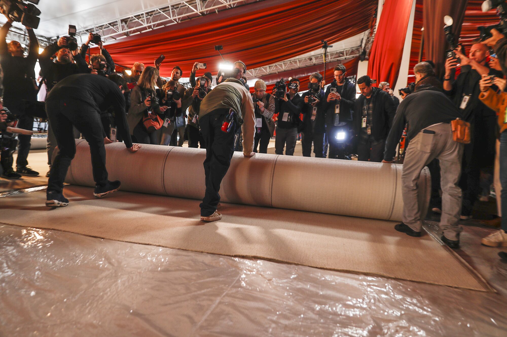 People roll out a large carpet with many people looking on