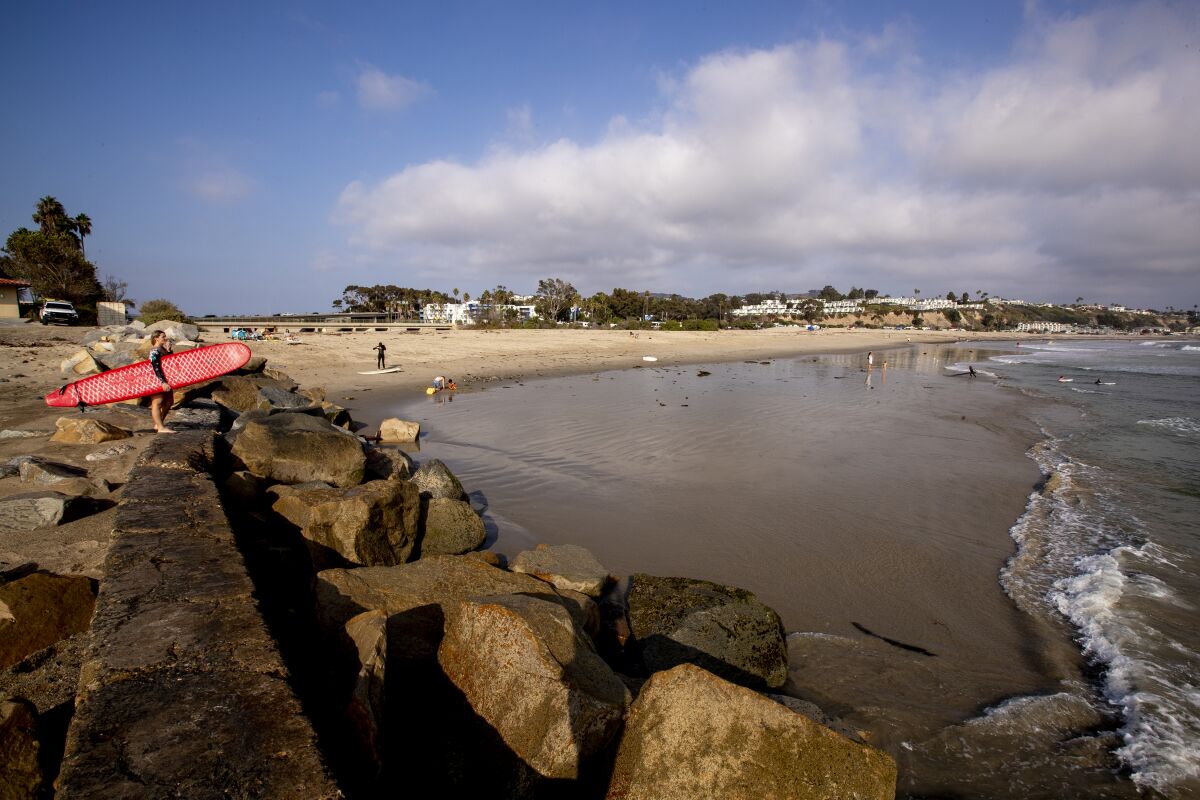 A surfer stands on the breakwater at Doheny State Beach.