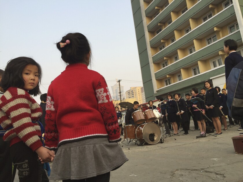 Girls watch schoolchildren play music to entertain and inspire people on their way home from work on March 29 in Pyongyang, North Korea. The government has called a loyalty drive before a ruling party congress in May.