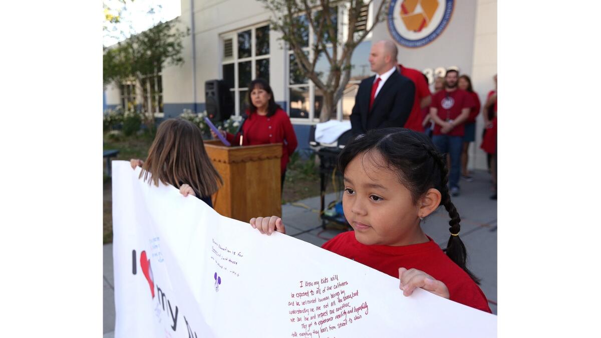 Nora Crivelli, 10, helps to hold up a banner at George Washington Elementary School in Burbank as part of the California Teachers Assn.'s “Day of Action.”