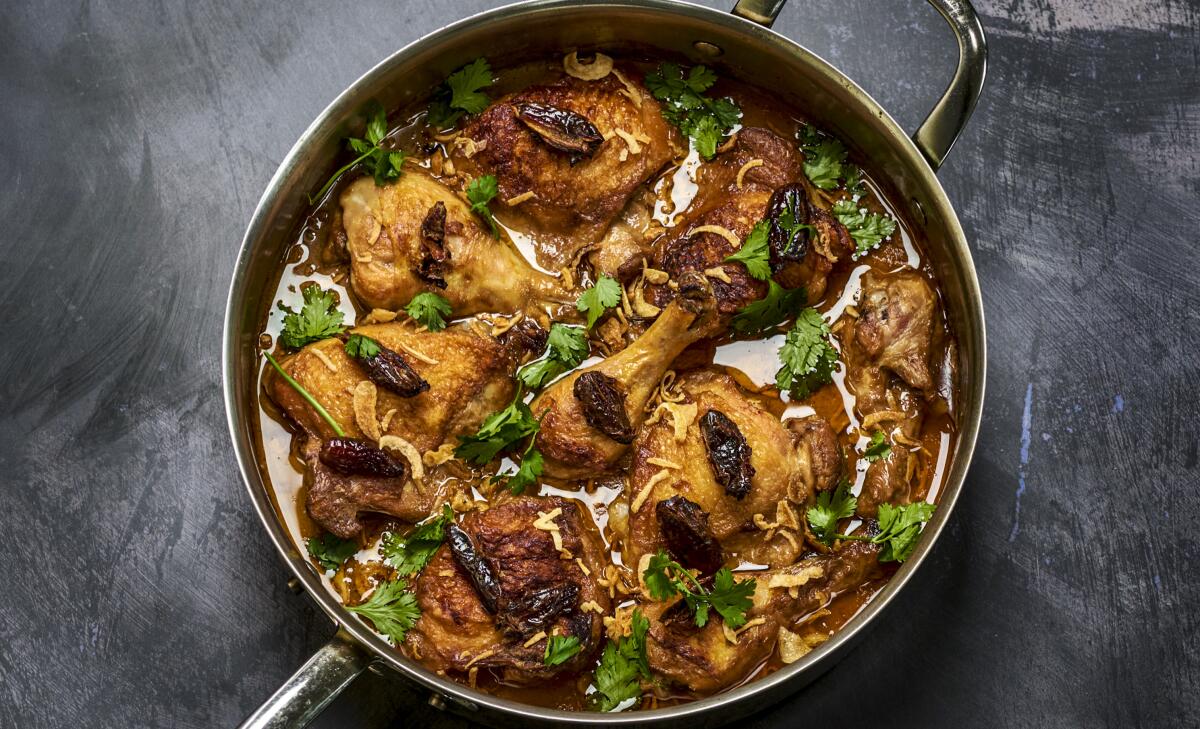 A metal pot filled with chicken in coconut milk with dates