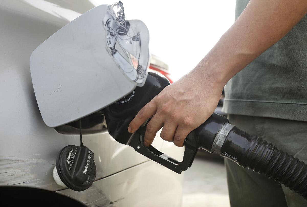 A person places a nozzle into a car's gas tank