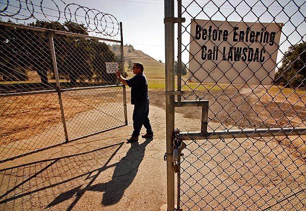 Roger Jeka with the L.A. Department of Water and Power locks the gates to the Chatsworth Nature Preserve, site of a proposed wetlands mitigation plan. Environmental groups led by the Southwest Herpetologists Society and the San Fernando Valley Audubon Society are fighting Los Angeles' proposal to transfer control of the preserve from the DWP to the Department of Recreation and Parks. They contend that such a move would adversely effect an unusually diverse collection of reptiles and amphibians in the area. See full story