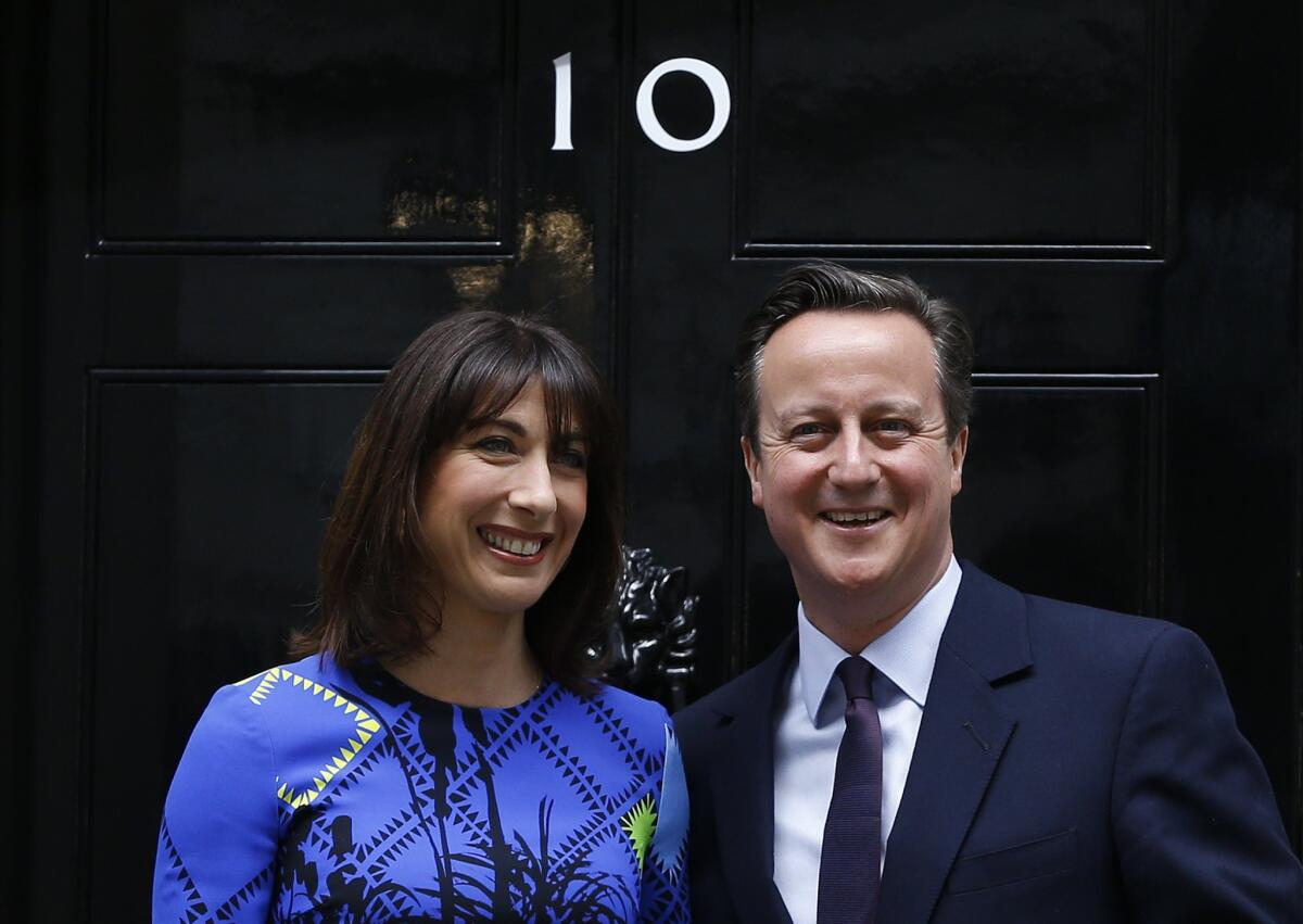 Prime Minister David Cameron and his wife, Samantha, smile from the steps of 10 Downing Street in London after meeting with Britain's Queen Elizabeth II in a traditional formality, where he informed her that he has enough support to form a government.