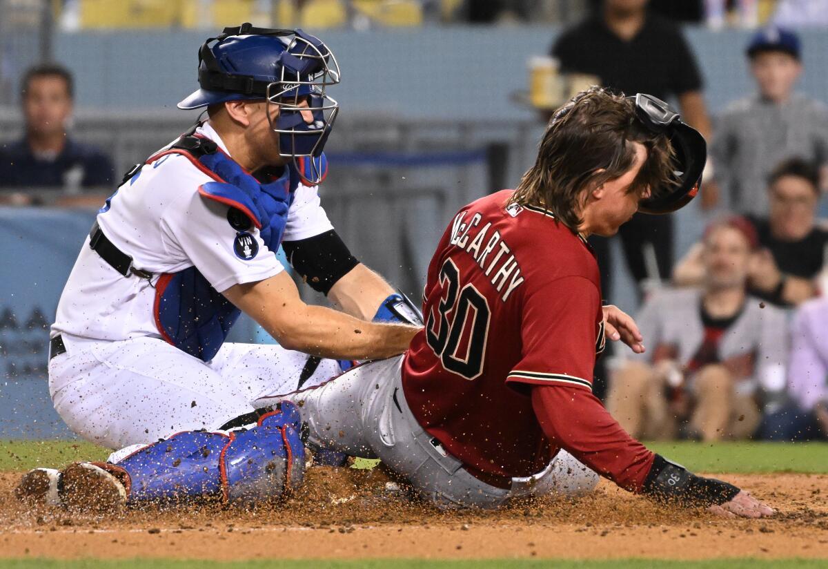 Arizona Diamondbacks Jake McCarthy beats the tag of Dodgers catcher Austin Barnes to score a run.