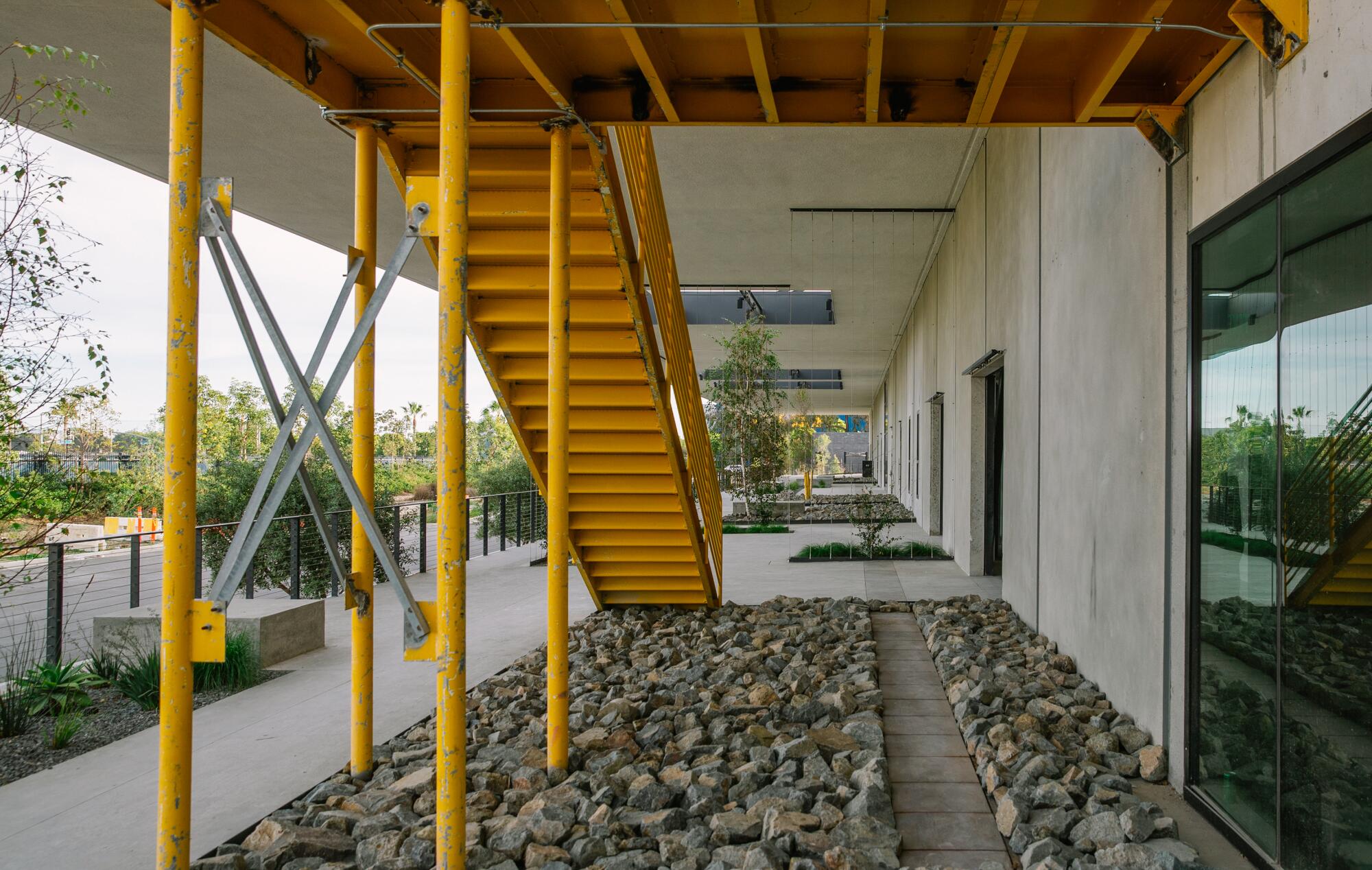 A view of yellow stair case descending into a rock garden on what was once a loading dock at the Press