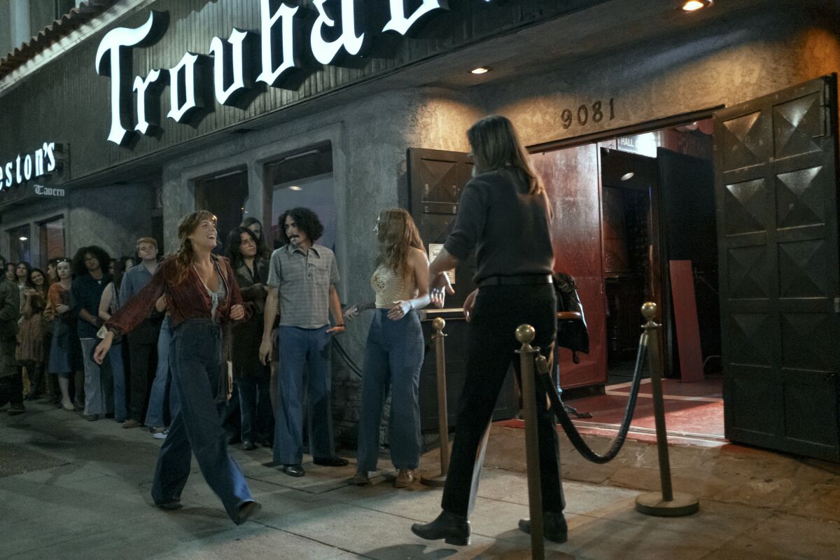 A woman bypasses the line to enter a music venue.