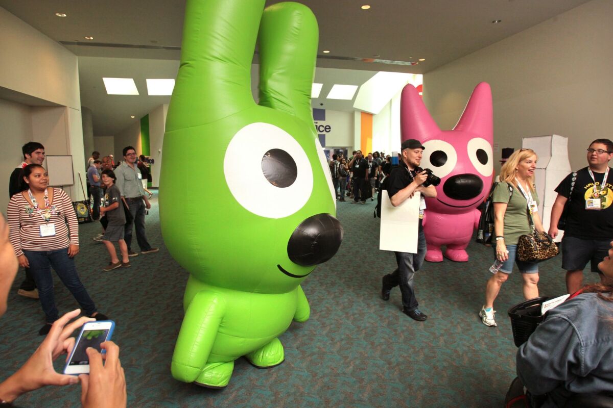 Inflatable characters "Yo-Yo," left, and "Hoops" stand in a corridor outside Comic-Con's main exhibit hall in 2013.