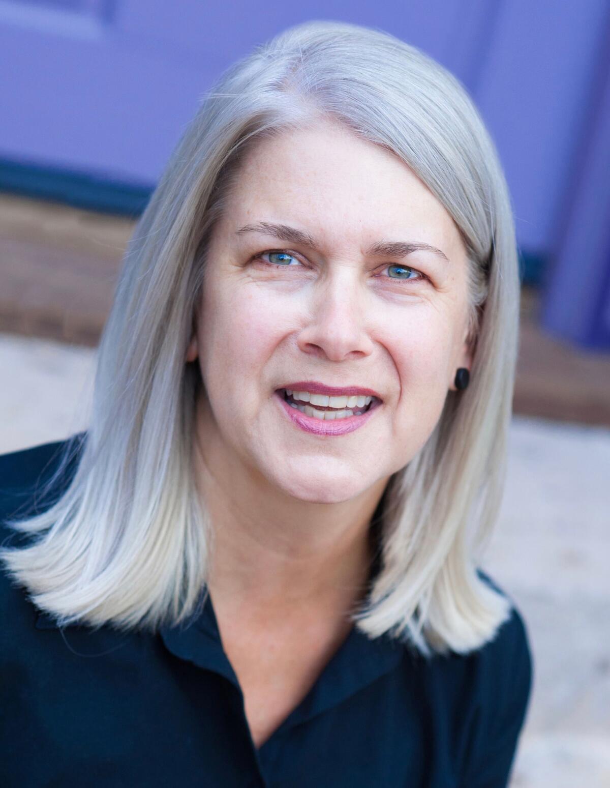 Portrait of a woman with shoulder length hair and black button-up shirt.