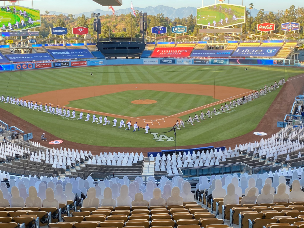 Baseball players kneel in a mostly empty stadium.