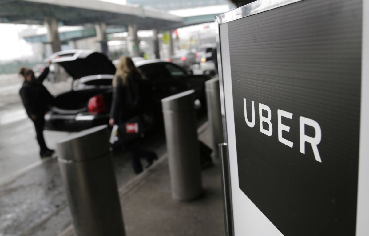 FILE - A sign marks a pick-up point for the Uber car service at LaGuardia Airport in New York on March 15, 2017. The federal government is suing Uber saying it discriminates against disabled people by charging fees when drivers have to wait for passengers to board their vehicles. (AP Photo/Seth Wenig, File)