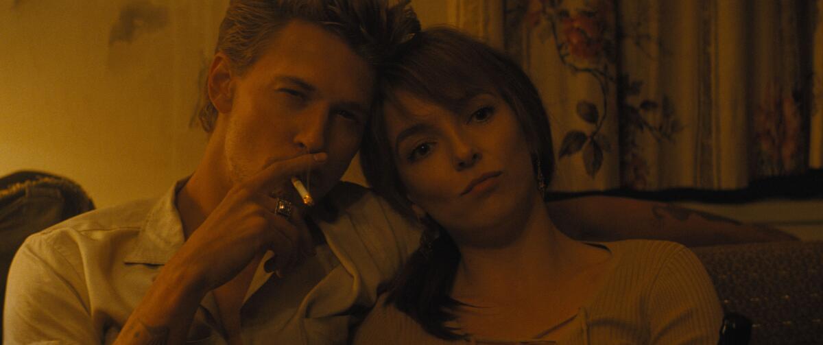 A smoking man sits with a woman.