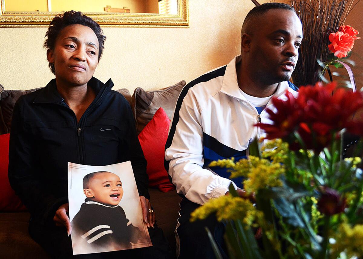 Chantel and Elwin Morris pose with a photo of their slain son, Taegrin, at their home outside Johannesburg.