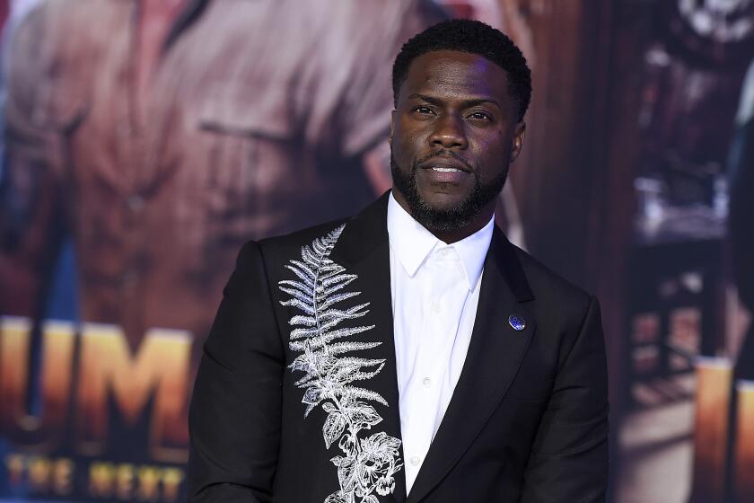 A man in a black jacket with a white fern stitched on a lapel poses at a movie premiere
