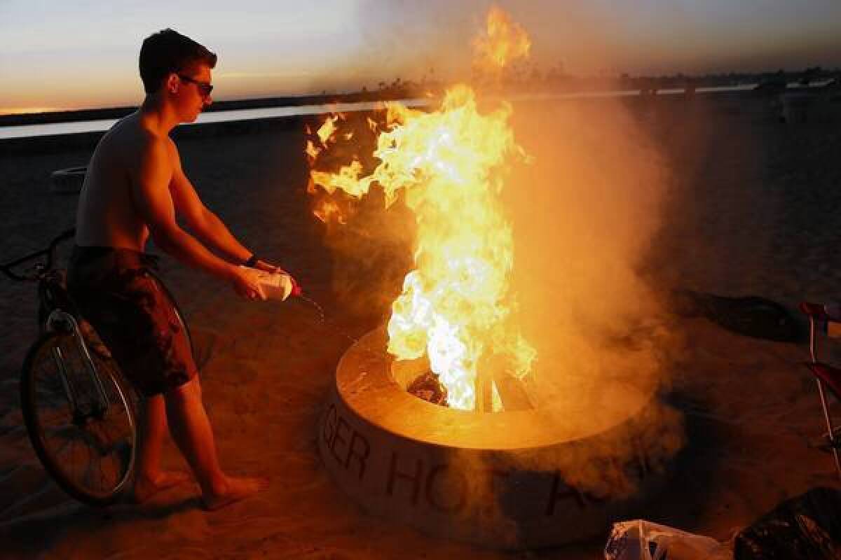 James Hughes adds fuel to the blaze in a fire ring at Corona Del Mar State Beach.