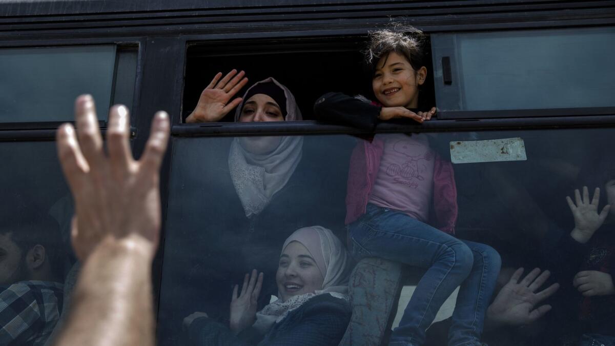 Emad Abu Safia waves goodbye to his children Nadeen Abu Safia, top, Dareen Abu Safia, bottom, after they managed to board the bus to the Rafah border crossing in the Gaza Strip.