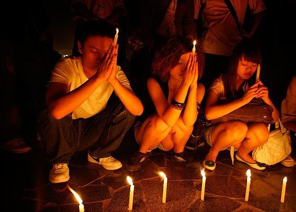 People hold candles in memory of earthquake victims at the People's Square in Chengdu, Sichuan province. Streets were eerily empty as many shops shut their doors in response to a government call for three days of public mourning.