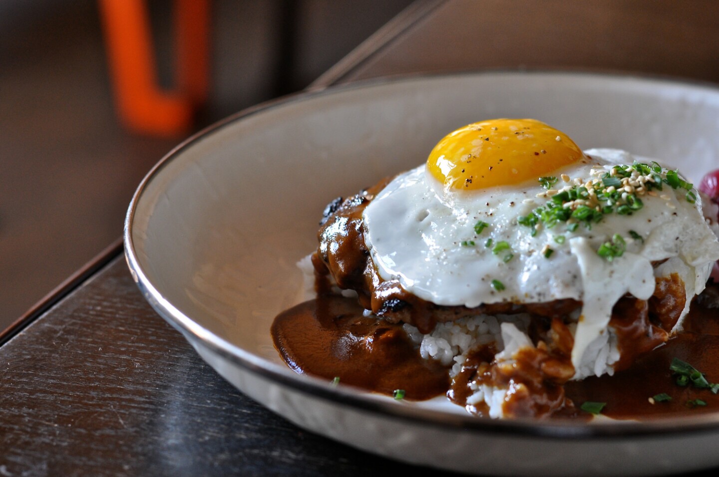 A-Frame's Loco Moco, with "hambagu" steak, rice, curry gravy, egg and pickled pearl onions, is shown.