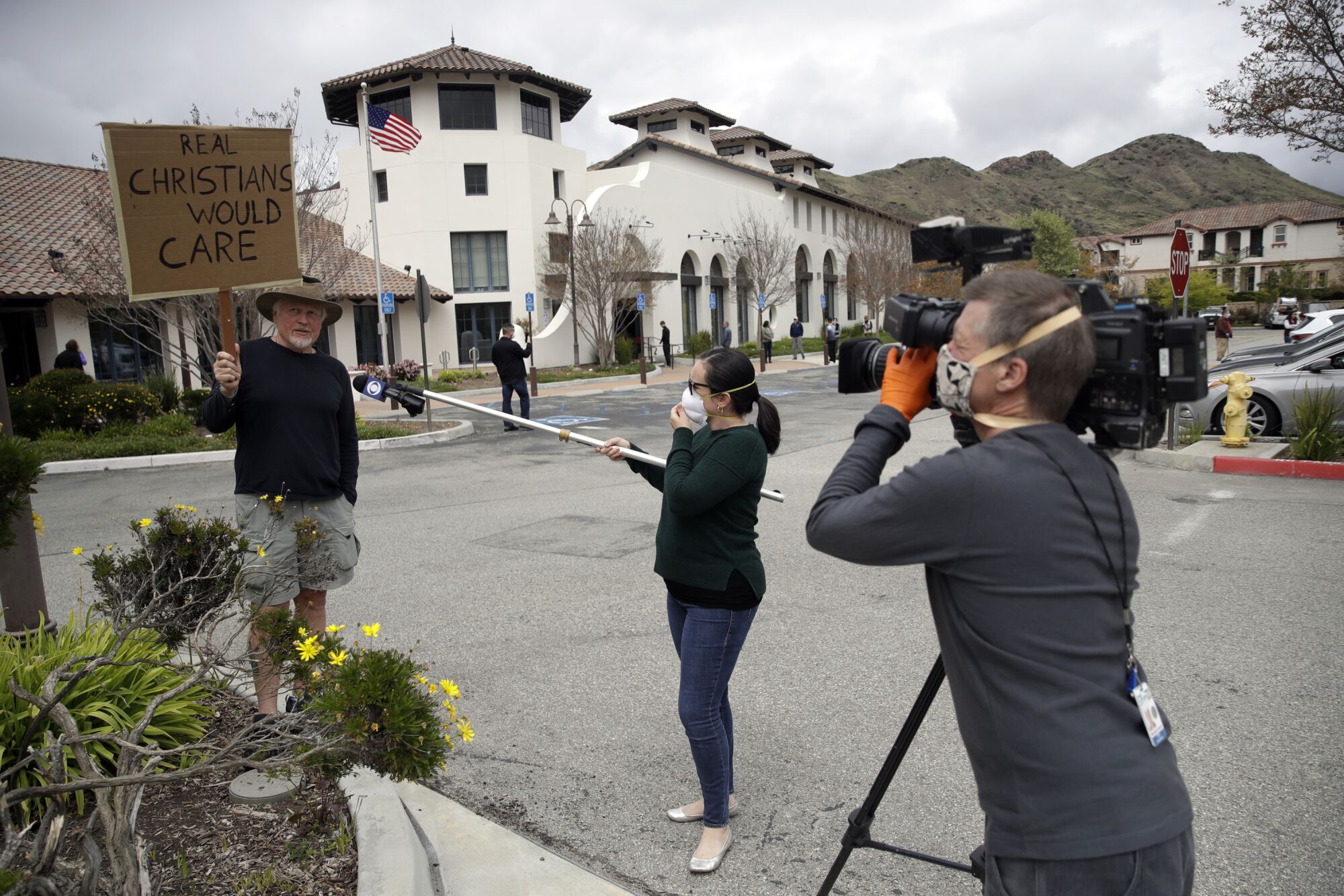 CALIFORNIA: Reporters practice social distancing as they interview Andrew Goetze, left, who protested a service at Godspeak Calvary Chapel on Sunday in Newbury Park, Calif.