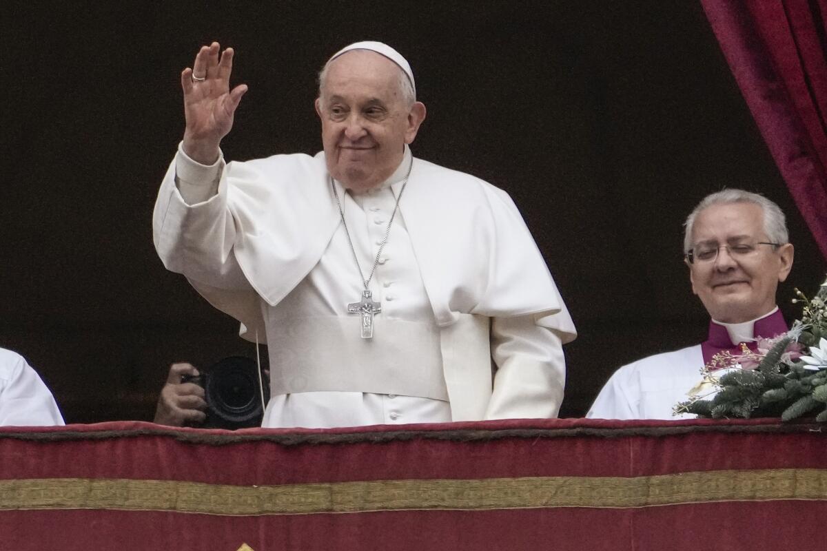 A smiling Pope Francis waves from the loggia of St. Peter’s Basilica  