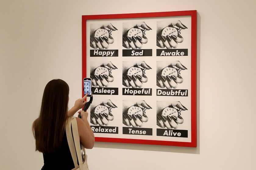 A visitor takes a photo of OUntitled, 1989O by Barbara Kruger of Newark, New Jersey at the art exhibit O13 WomenO during the grand opening of the new Orange County Museum of Art in Costa Mesa on Wednesday. (Kevin Chang / Daily Pilot)