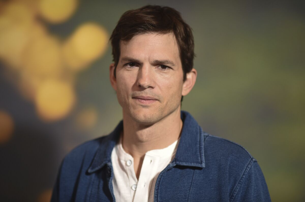 A man with short brown hair in a white shirt and dark blue jacket.