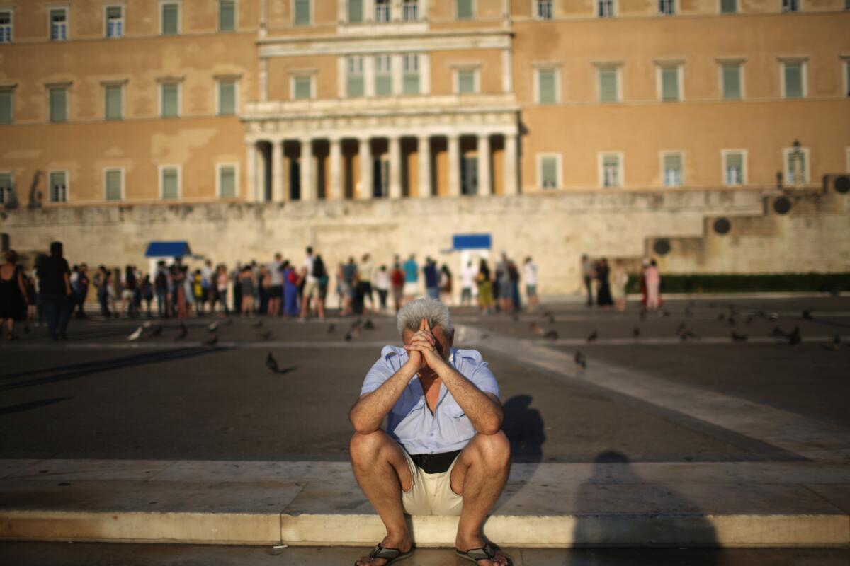 A man sits alone as protesters gather outside the Greek Parliament building in Athens on July 13 to demonstrate against austerity after an agreement for a third bailout with Eurozone leaders.