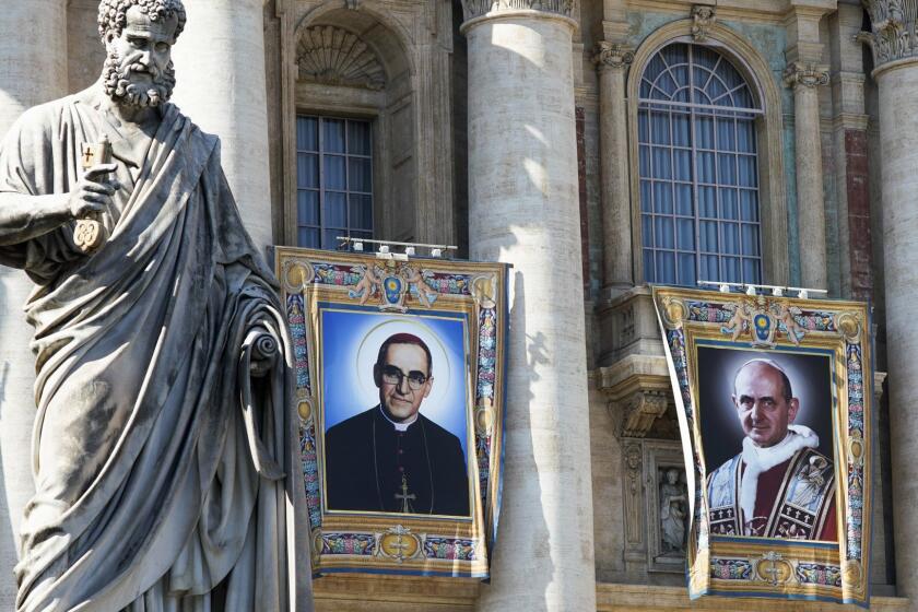 The tapestries of Roman Catholic Archbishop Oscar Romero, left, and Pope Paul VI hang from a balcony of the facade of St. Peter's Basilica at the Vatican, Saturday, Oct. 13, 2018. Pope Francis will canonize two of the most important and contested figures of the 20th-century Catholic Church, declaring Pope Paul VI and the martyred Salvadoran Archbishop Oscar Romero as models of saintliness for the faithful today. (AP Photo/Andrew Medichini)