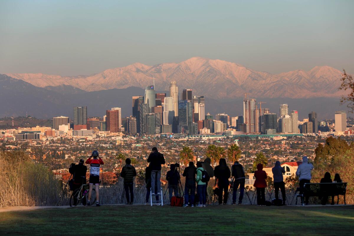 People view downtown Los Angeles with the San Gabriel mountains shown in the background