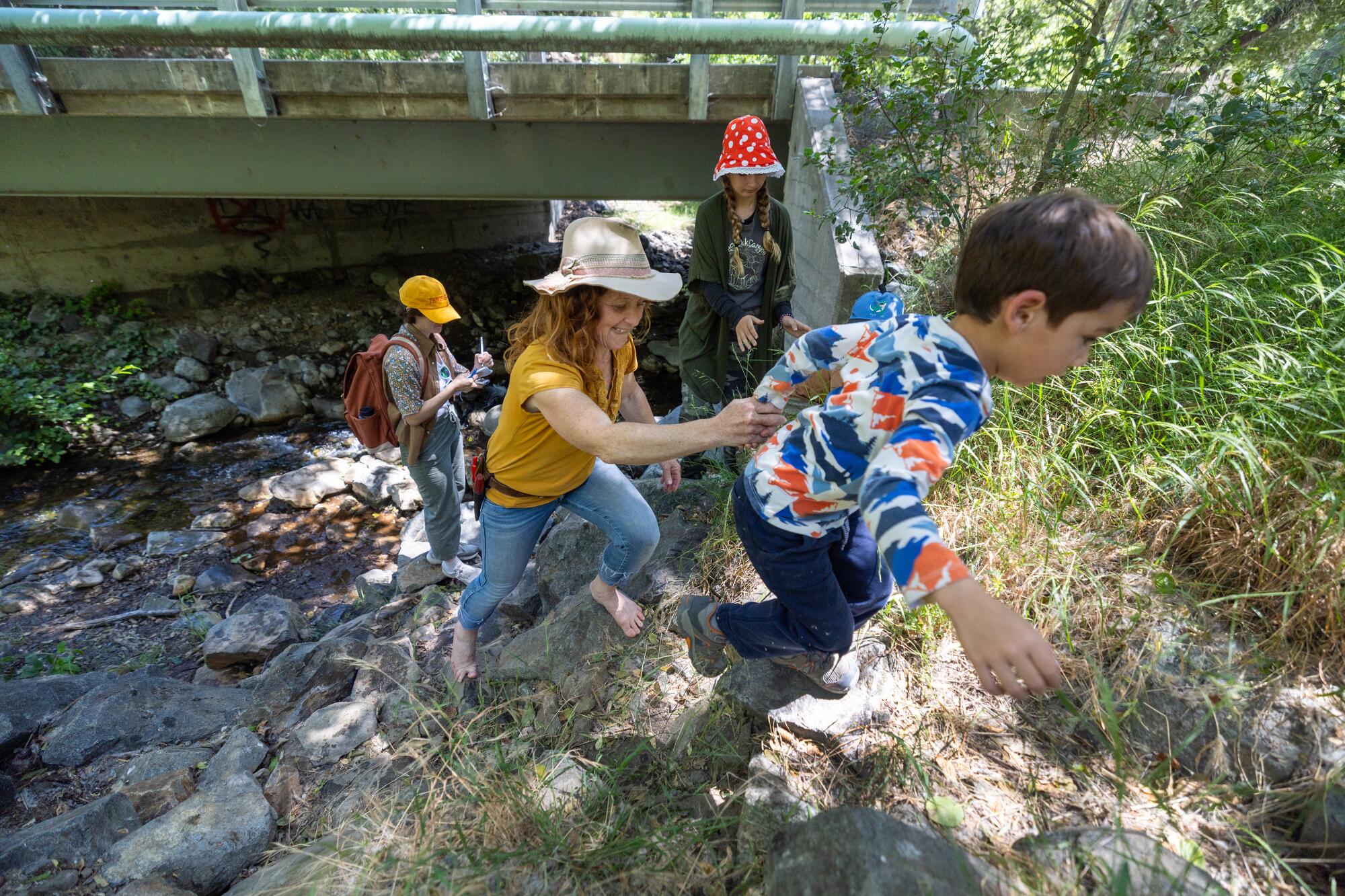 Children climb a riverbank.