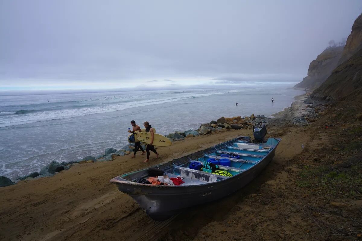 Surfers walk past one of two pangas