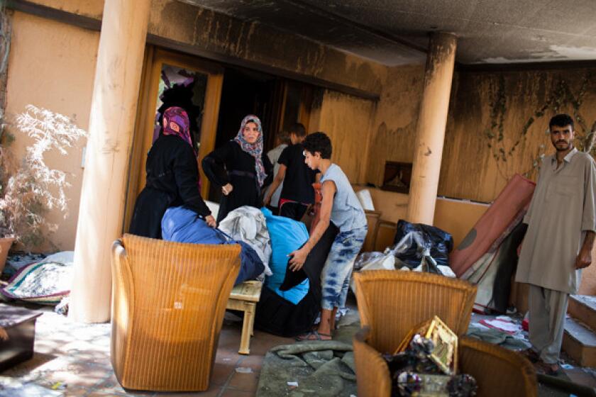 People gather articles collected from inside a house at Baba al Azizia, Muammar Gaddafi's main military compound on August 27, 2011 in Tripoli, Libya.