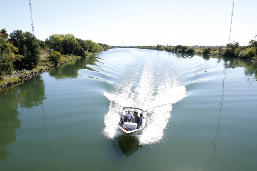 FILE — In this Monday, Sept. 23, 2013 file photo, a boat cruises down the Delta Cross Channel between the Sacramento River and Snodgrass Slough near Walnut Grove, Calif. California officials announced Thursday, Nov. 21, 2019 that they will sue the Trump administration to block its recently announced rules governing water in the San Joaquin Delta. (AP Photo/Rich Pedroncelli, File)