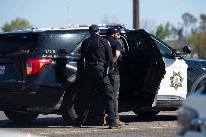 A man is escorted to a sheriffs vehicle after a shooting at the Sacramento Sikh Society Temple, it is unknown if he was involved, on Sunday, March 26, 2023, in Sacramento. The shooting occurred during the Sacramento Sikh Societys first Nagar Kirtan Parade.