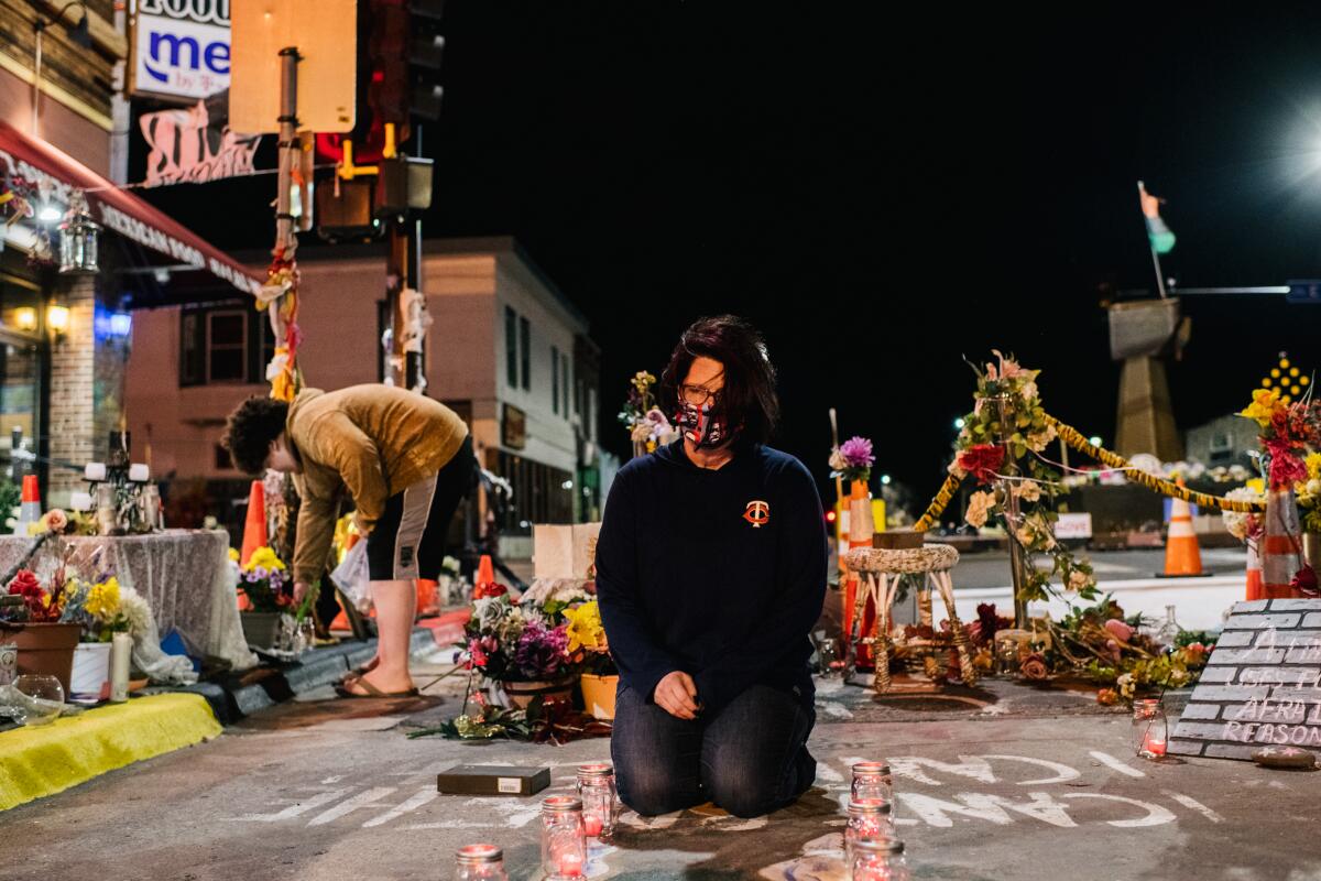 George Floyd's girlfriend kneeling at the site of his death amid flowers and candles. 