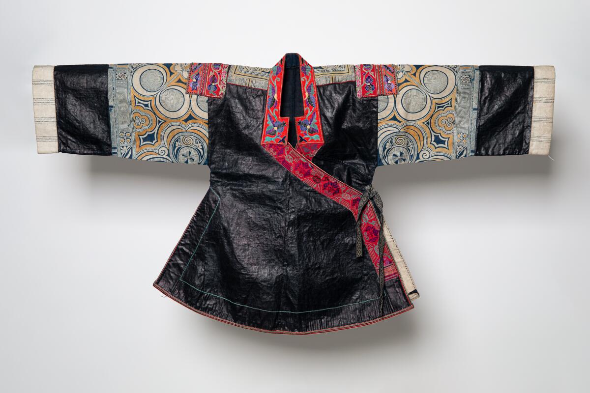 A Hmong indigo-dyed jacket has an inky blue chest and bright red border, with concentric circles on the arms.