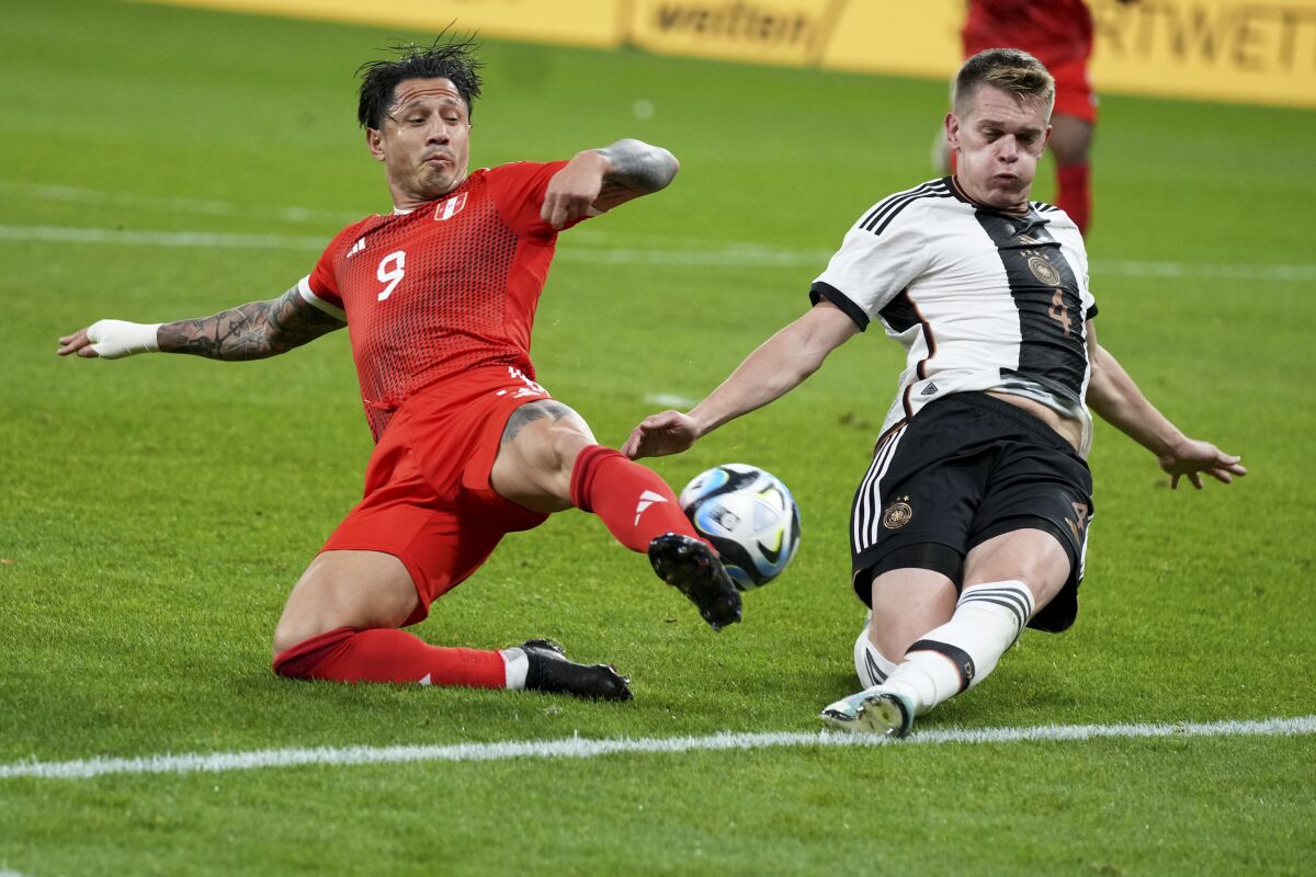 Peru's Gianluca Lapadula vies for the ball with Germany's Matthias Ginter, right, during the international friendly soccer match between Germany and Peru at the Opel Arena in Mainz, Germany, Saturday, March 25, 2023. (AP Photo/Michael Probst)