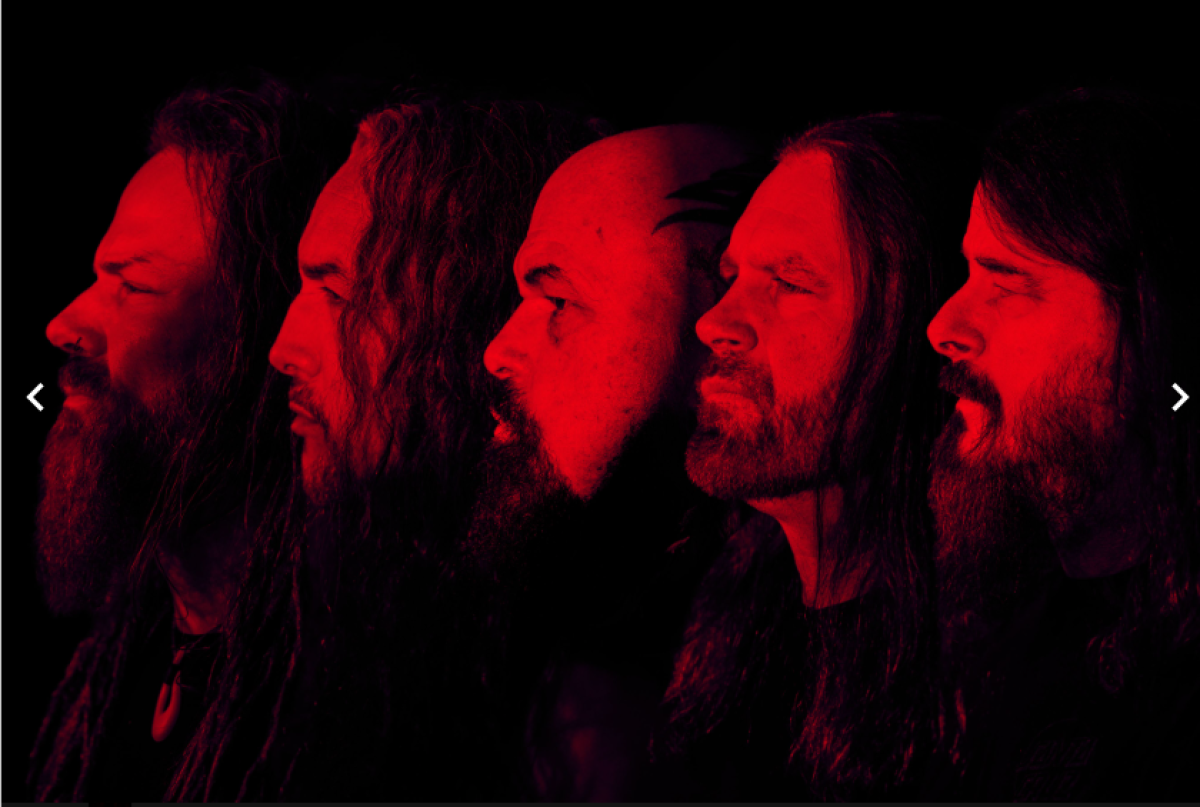 Five men bathed in red light  line up for a photo.