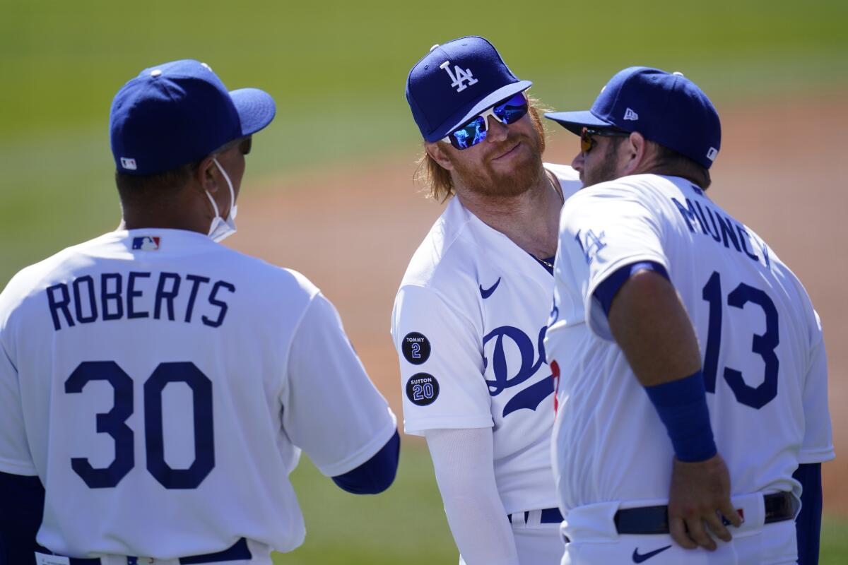 Dodgers manager Dave Roberts speaks with Justin Turner and Max Muncy before a spring training game.
