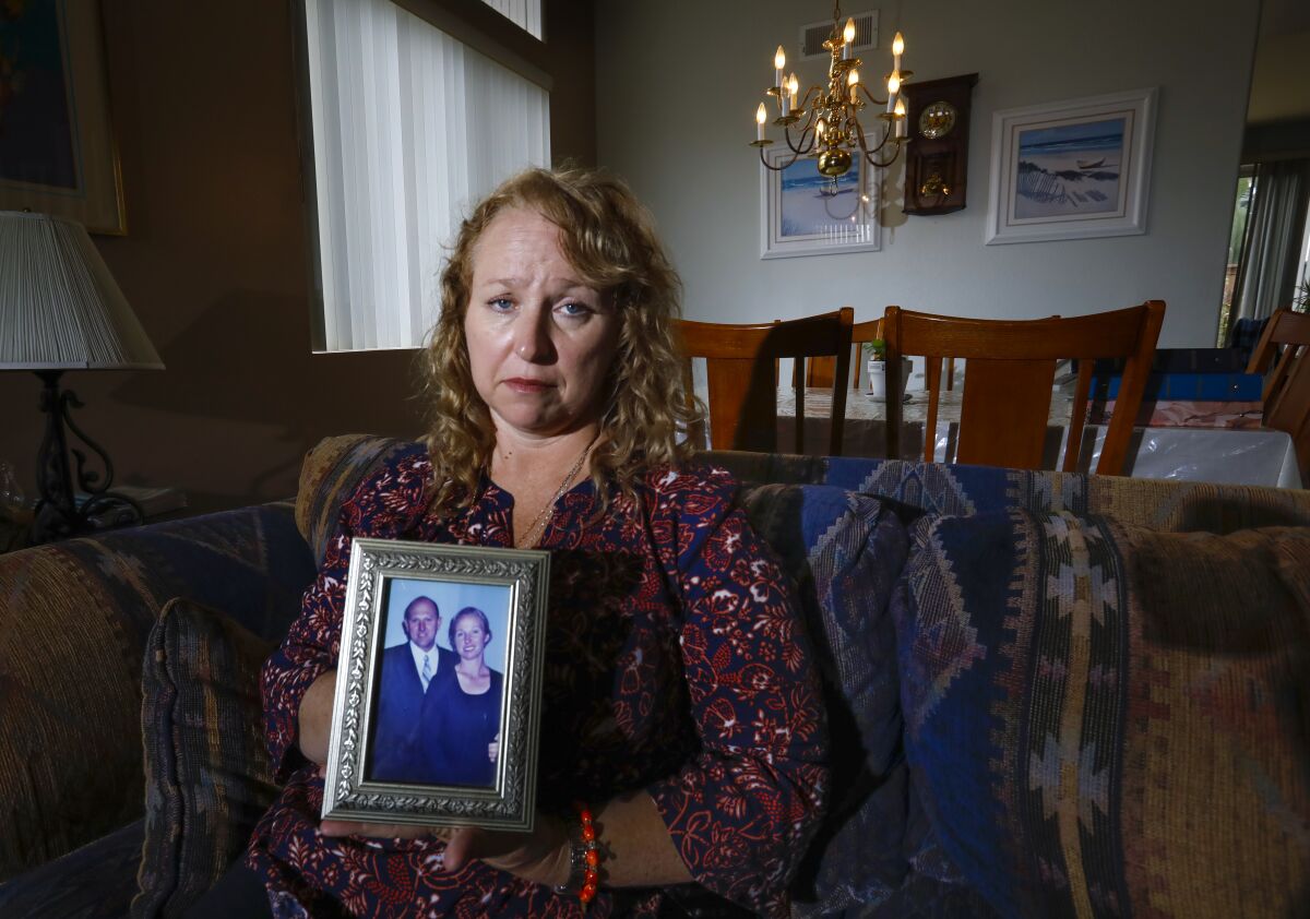 Theresa Sturkie holds a photo of she and her husband of 21 years, John Sturkie, at her home on May 21, 2019 in Oceanside