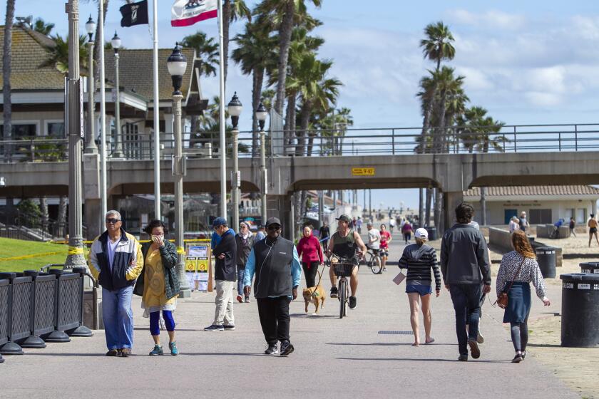 People walk along the path near the Huntington Beach Pier on Tuesday, March 24.