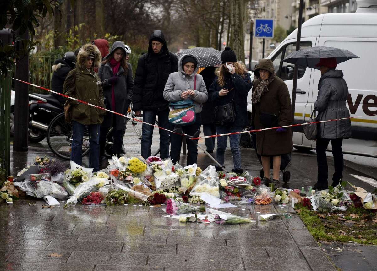Floral tributes are laid on the ground during a minute of silence in Paris on Jan. 8, a day after two gunmen stormed the offices of the satirical magazine Charlie Hebdo and killed 12 people.