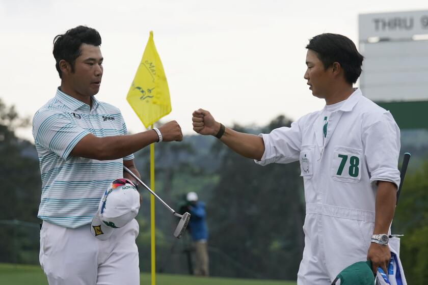 Hideki Matsuyama is congratulated by caddie Shota Hayafuji after shooting a seven-under 65 at the Masters on April 10, 2021.